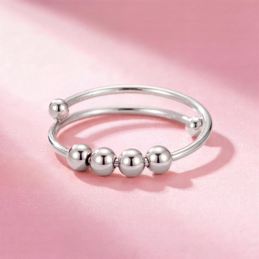 Fidget Beads Ring Silber mit vier drehbaren Perlen auf rosa Hintergrund