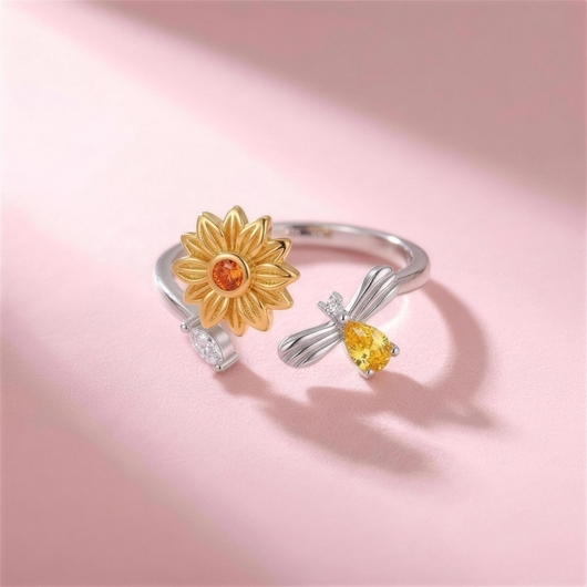 Bee Ring – silberfarbener verstellbarer Ring mit goldener Sonnenblume und Biene, liegend auf rosa Hintergrund